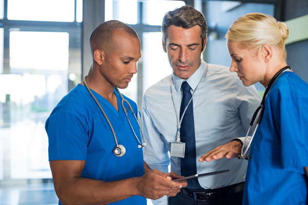Image of ethnic male and Caucasian female nurse talking to a male doctor