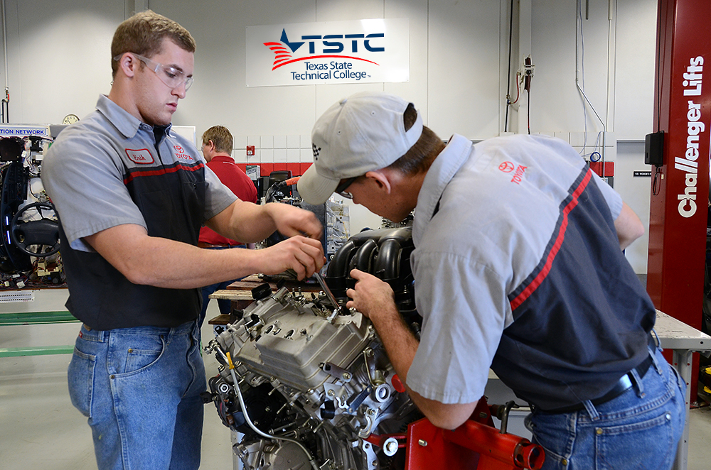two male diesel technology students working on an engine in the lab
